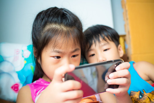 Children friend girls and boy group playing internet with mobile smartphone in room
