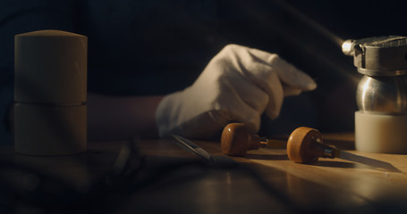 Various jeweler tools on the table with jewelers hand in a white glove
