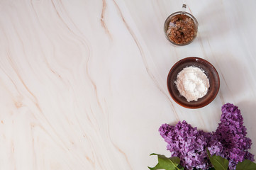 Natural home skin care. Ingredients of a face mask. Decoction of lilac flowers (Syringa vulgaris) and potato starch on a marble background. Free space. Top view.