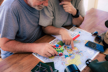 Happy senior couple planning travel around the world - active elderly vacation, free retirement concept. Wooden table with camera, mobile phone, passports