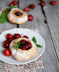 homemade sweet buns filled with cherry decorated with mint and icing sugar on wooden table close-up