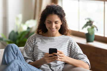 Close up smiling young woman looking at smartphone screen, chatting in social network or surfing...