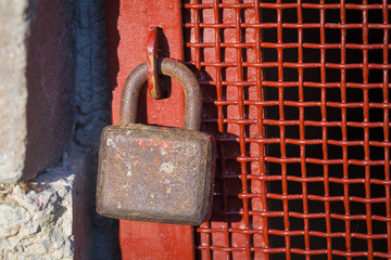 Old rusty padlock on an iron door.