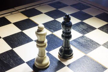 the chessboard with Black king and white queen facing in understanding concept