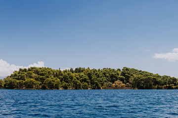 Fototapeta na wymiar Greek Island viewed from the sea. Beautiful sea landscapes on Island in Greece. famous Scorpios island, from the left side is Lefkada island and from right is a part of gorgeous Meganisi island.