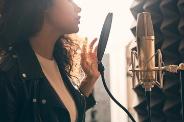Pretty female singer recording in music studio