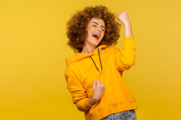 Hurray, I did it! Portrait of ecstatic enthusiastic curly-haired woman in urban style hoodie...