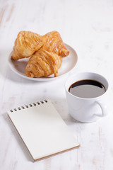 cup of hot coffee with croissant on white wooden background.  Working at home concept.
