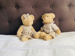 couple d'ours en peluche l'un contre l'autre sur un lit
