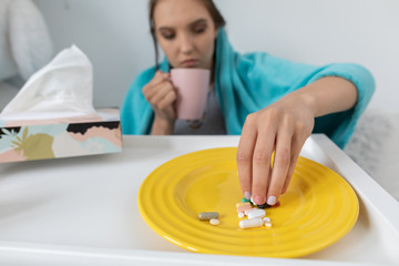 On the plate lies a set of tablets and vitamins as well as antibiotics that are necessary during...