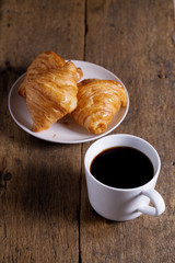 cup of hot coffee  with croissant on dark wooden background.  Working at home concept.