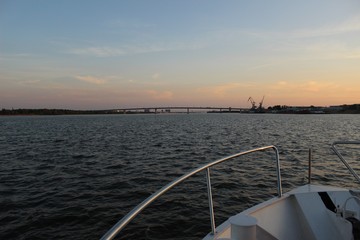 Sunset over the river from the ship, over which there is a large bridge.