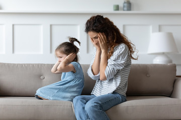 Stubborn spoiled little girl covering closing ears with hands, ignoring hopeless upset mother, parent and child, family generations conflict, complicated relationship between single mum and daughter