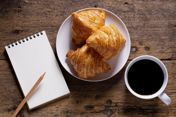 cup of hot coffee  with croissant on dark wooden background.  Working at home concept.
