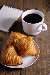 cup of hot coffee  with croissant on dark wooden background.  Working at home concept.