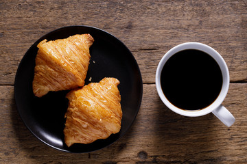 cup of hot coffee  with croissant on dark wooden background.  Working at home concept.