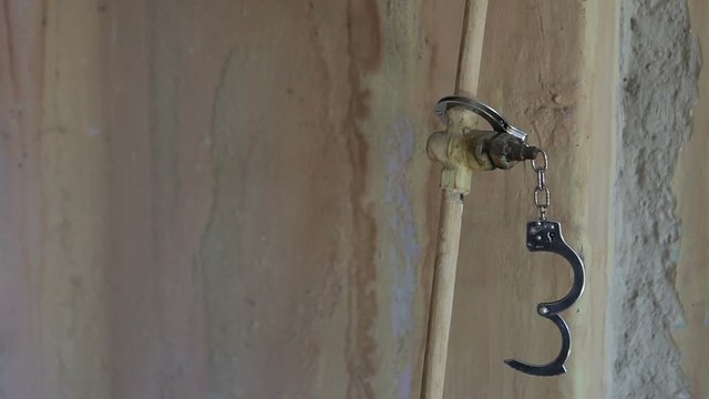 Handcuffs are fastened to a metal pipe.