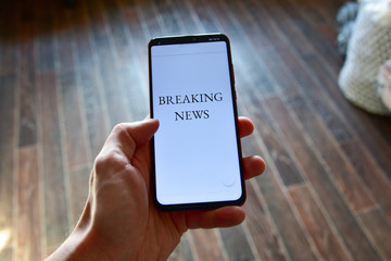close up man's hand holding mobile phone device with news feed