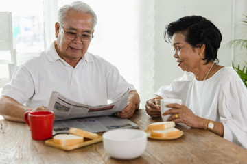 Obraz na płótnie Canvas An Asian elderly couple reading a newspaper.