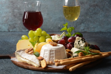 Cheese platter with assorted cheeses, grapes, nuts and snacks . Italian, French cheese starter. Traditional Shavuot Jewish Holiday food concept
