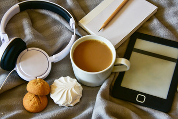 morning breakfast coffee with marshmallows, headphones, notebook with pencil, e-book, on a cozy plaid