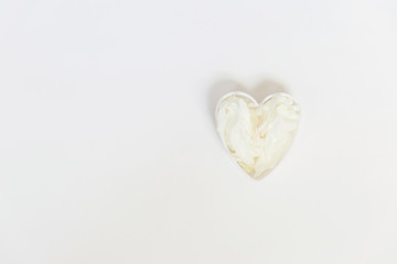 Heart shaped White peony petals decor. Peony flowers petals flat lay on a white background. Beautiful minimalistic white flowers close-up photo.