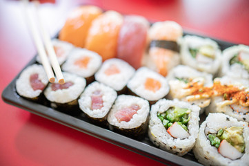 Japanese take away food.Set of sushi with chopsticks.Red background