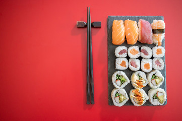 Set of sushi and maki roll.Sushi rolls set with tuna and salmon fish and black chopsticks isolated on red background.Top view.Copy space