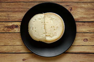 Cheese, Torta del Casar open, on black plate on wooden background top view