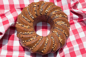bundt cake with chocolate and hazelnut crocant decor, red and white checkered textile background