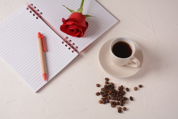 Cup of coffee, notebook, pen and rose flowers. Morning coffee break
