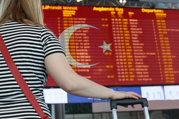 Fototapeta na wymiar Woman looks at the scoreboard at the airport. Select a country Turkey for travel or migration.