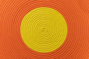 handmade round orange cotton knitted rug with yellow circle in the center, top view, directly above