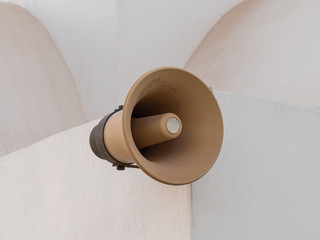 Old street loudspeaker attached to the wall of the old white church