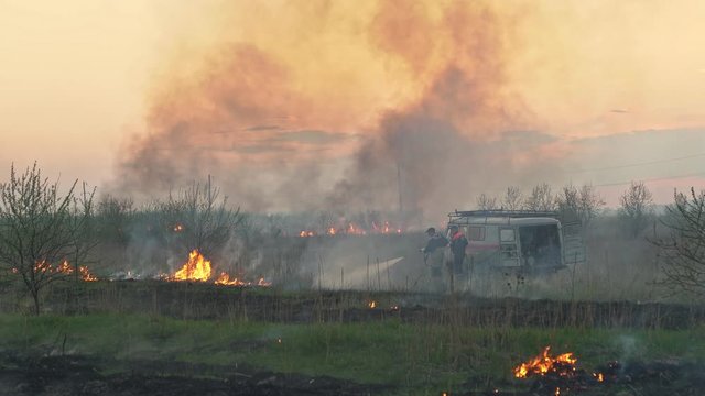 burns dry grass in sky smoke. firefighters car