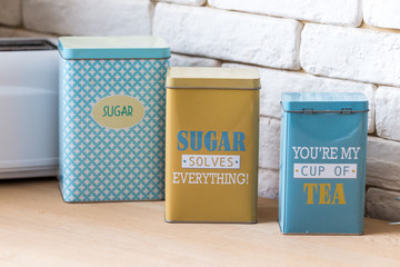 Kitchen cans for salt, pepper and sugar from metal are painted in blue and yellow for kitchen comfort.