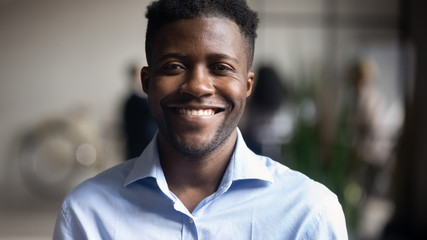 Head shot portrait close up smiling African American businessman employee in office looking at...