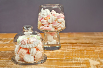Sweets in a glass on a wooden table. Transparent utensils with marshmallows and biz on a shabby old...