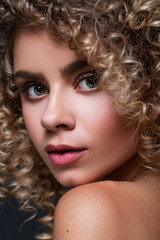 Cute cheerful woman close up portrait with afro curly hairstyle on a black background. Fresh, flawless skin