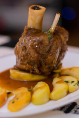 Baked pork knuckle recipe with golden apple slices, thyme, vegetables and white wine