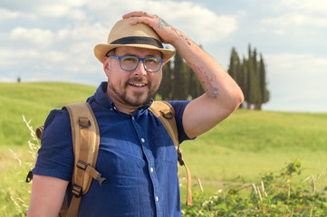 Young beautiful man Trekking in Tuscany and Italian medieval towns with a backpack