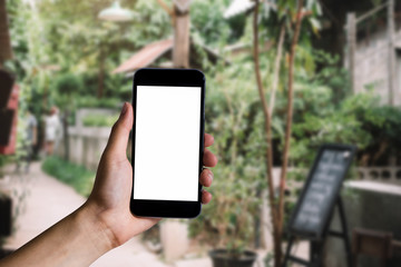 Hand holding white mobile phone with blank white screen in cafe.