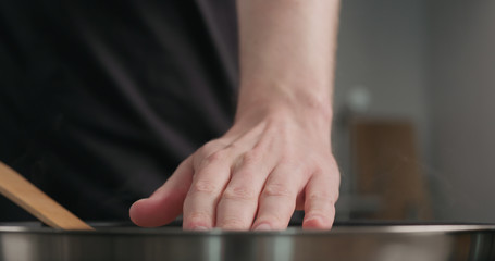 man hand check heat from frying pan