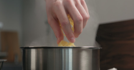 man hand put fettuccine pasta in saucepan with boiling water