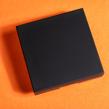 Professional colorful eye shadows for make up in plastic box on orange background. Mock up image with space for text