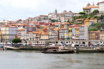 Fototapeta na wymiar Porto, Portugal - 23 June, 2019: Traditional boats anchored on the Douro River with the Cais da Ribeira in the background, in the city of Porto, Portugal