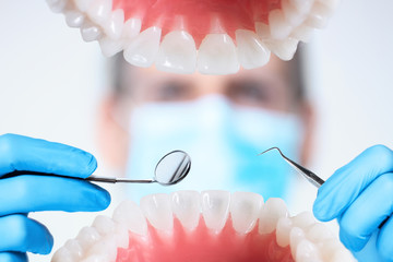 Closeup of open human jaw with teeth. Portrait of man dentist orthodontist doctor in medical mask...