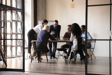 Diverse employees team engaged in teamwork in modern boardroom, sitting at table in office, reading legal documents, analyzing project statistics, financial report, discussing strategy, planning