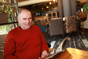 Senior man with menu book in restaurant