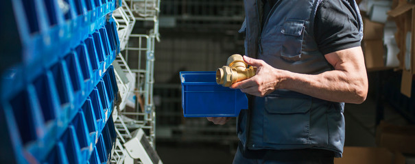Deliver,б man holds in his hand a gold-colored metal detail. Plumbing and materials. Widescreen...